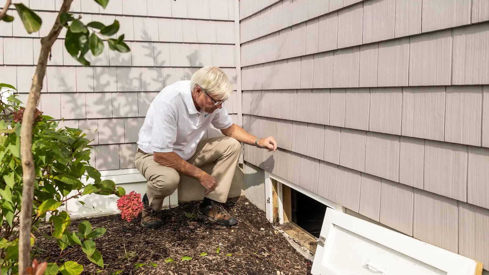 Home inspector examining a crawl space entrance