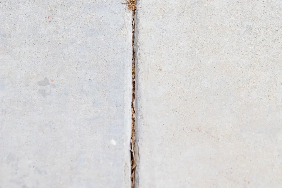 Cracked joint between concrete sidewalk slabs